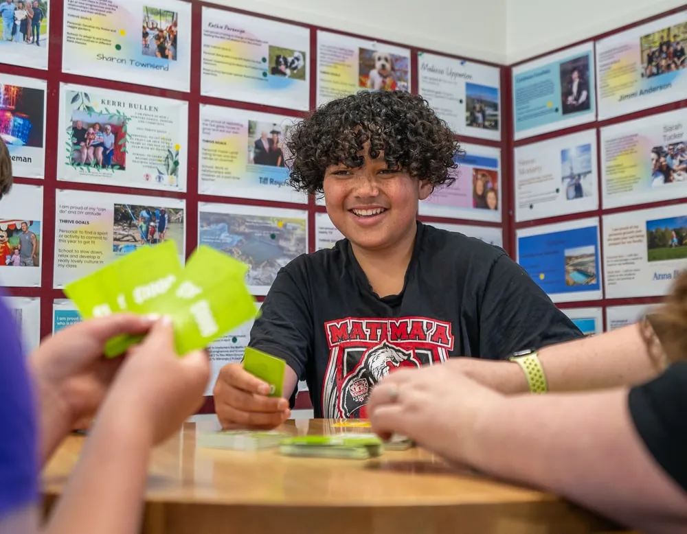 A smiling boy holding up Stack 'n Steal cards at a table