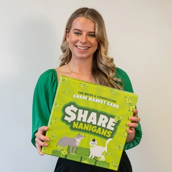 A smiling woman holding up a box of Sharenanigans